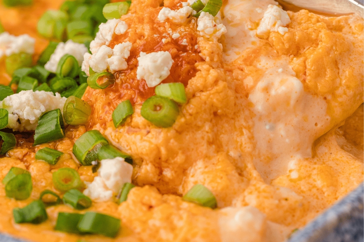 A bowl of cheesy dip with green onions.
