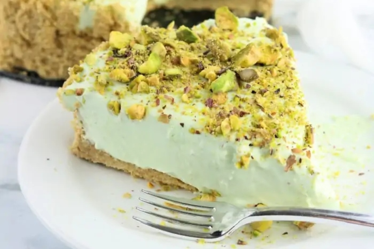 A slice of green pistachio cheesecake on a plate.