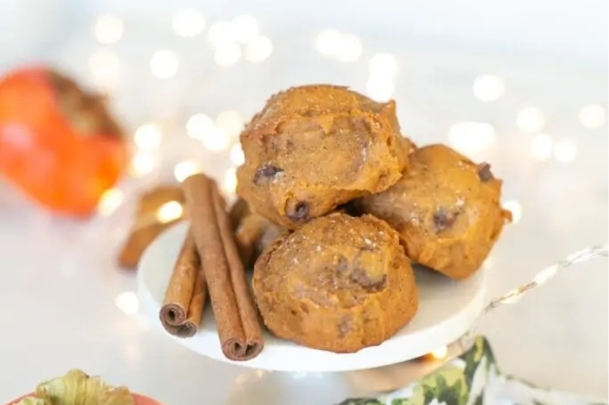 A plate of pumpkin muffins with cinnamon sticks and pomegranate seeds.