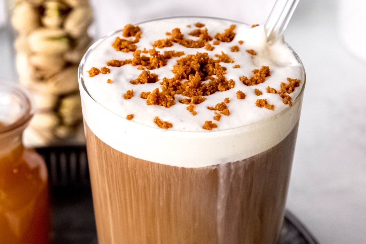 A coffee latte with whipped cream and nuts.