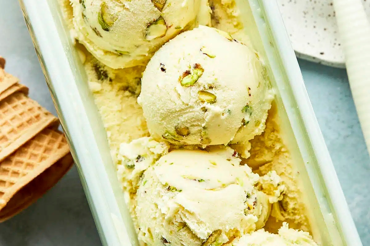 Three scoops of ice cream with pistachios and waffle cones.