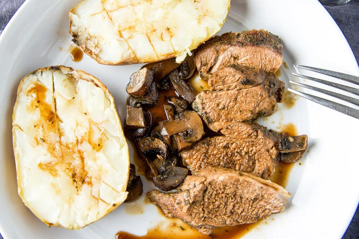 Steak with mushrooms and potatoes on a plate.