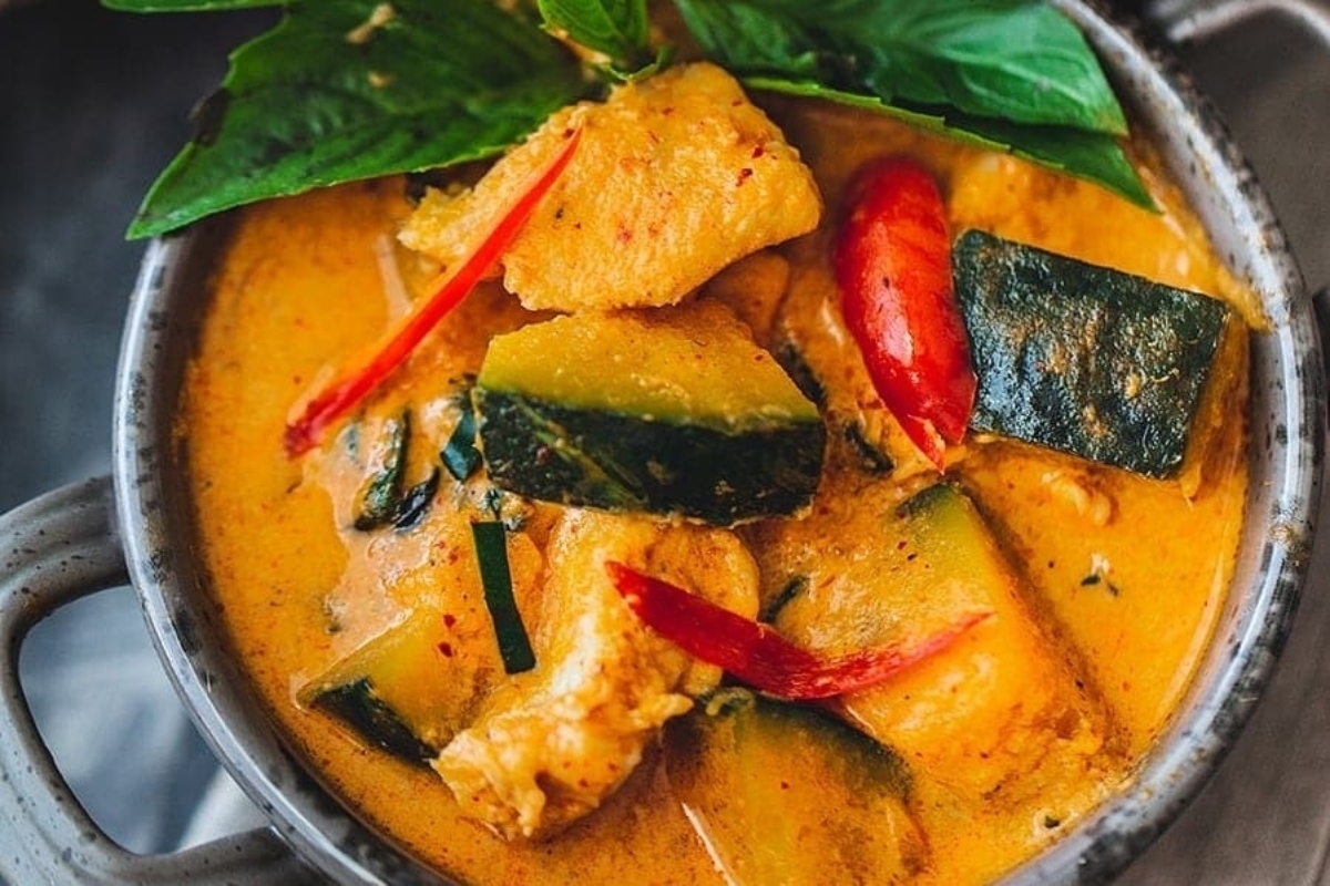 A bowl of thai curry with vegetables in it.