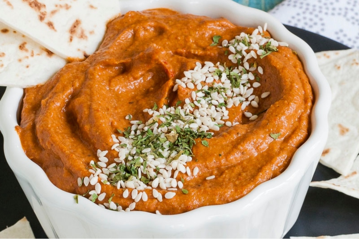 A bowl of hummus with pita chips.