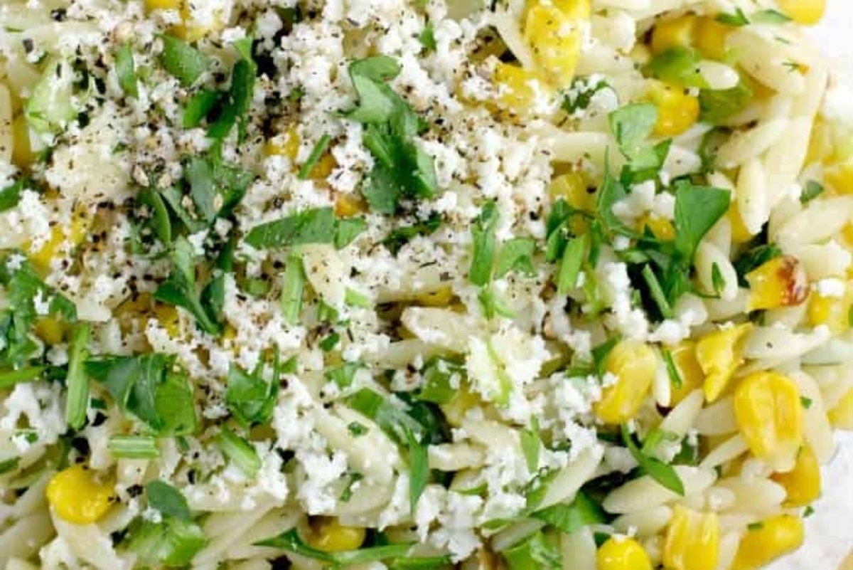A plate of pasta with corn and herbs.