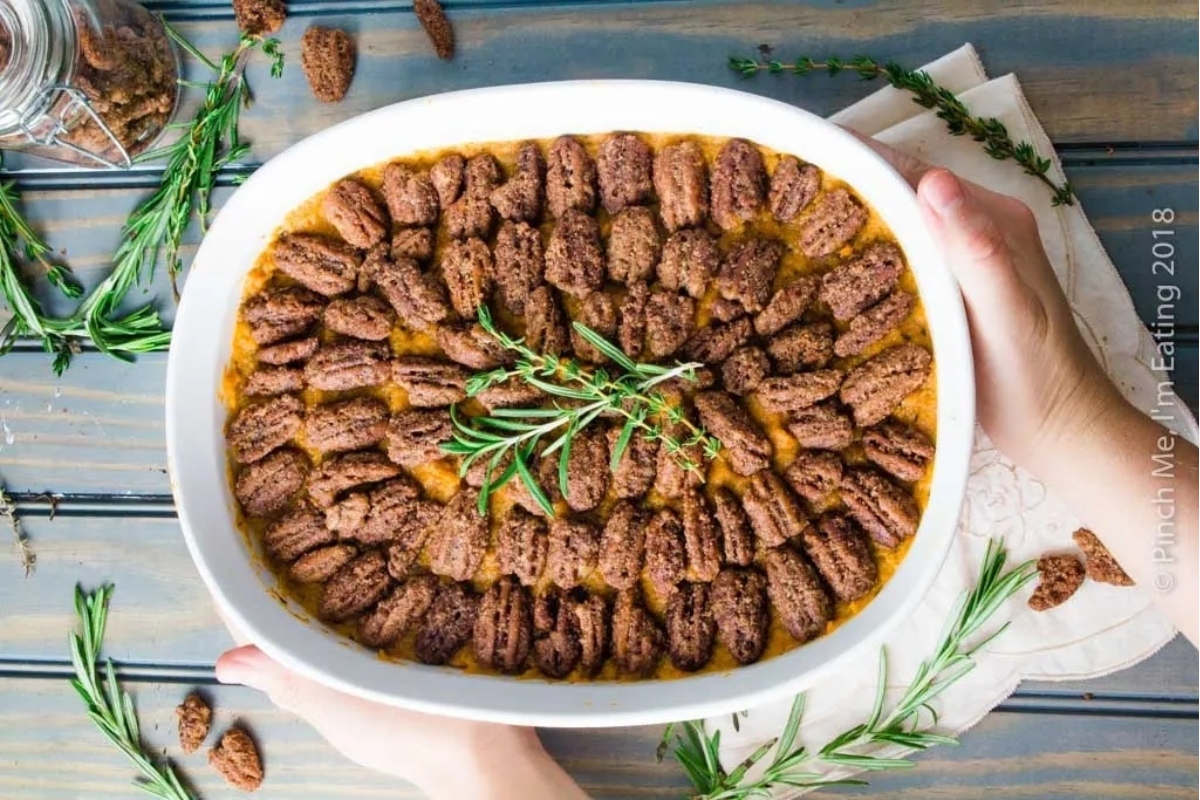 A dish with pecans and rosemary sprigs.