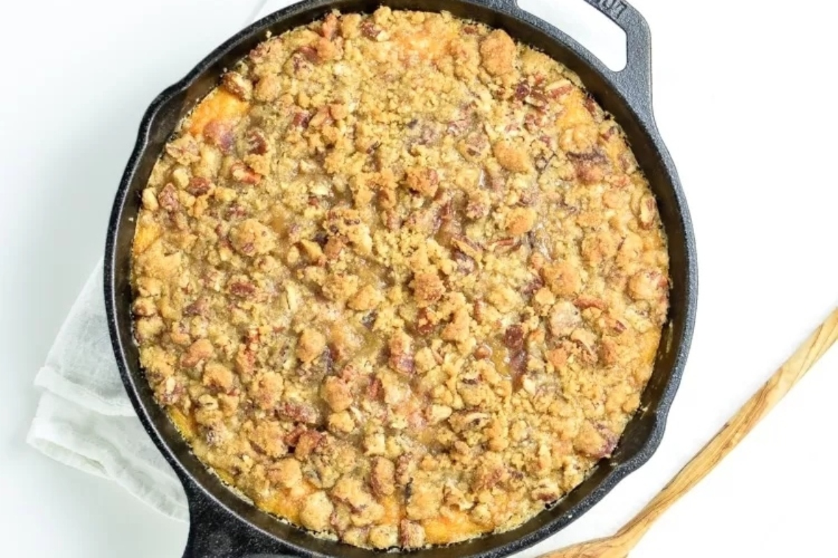 Sweet potato casserole in a skillet with a wooden spoon.
