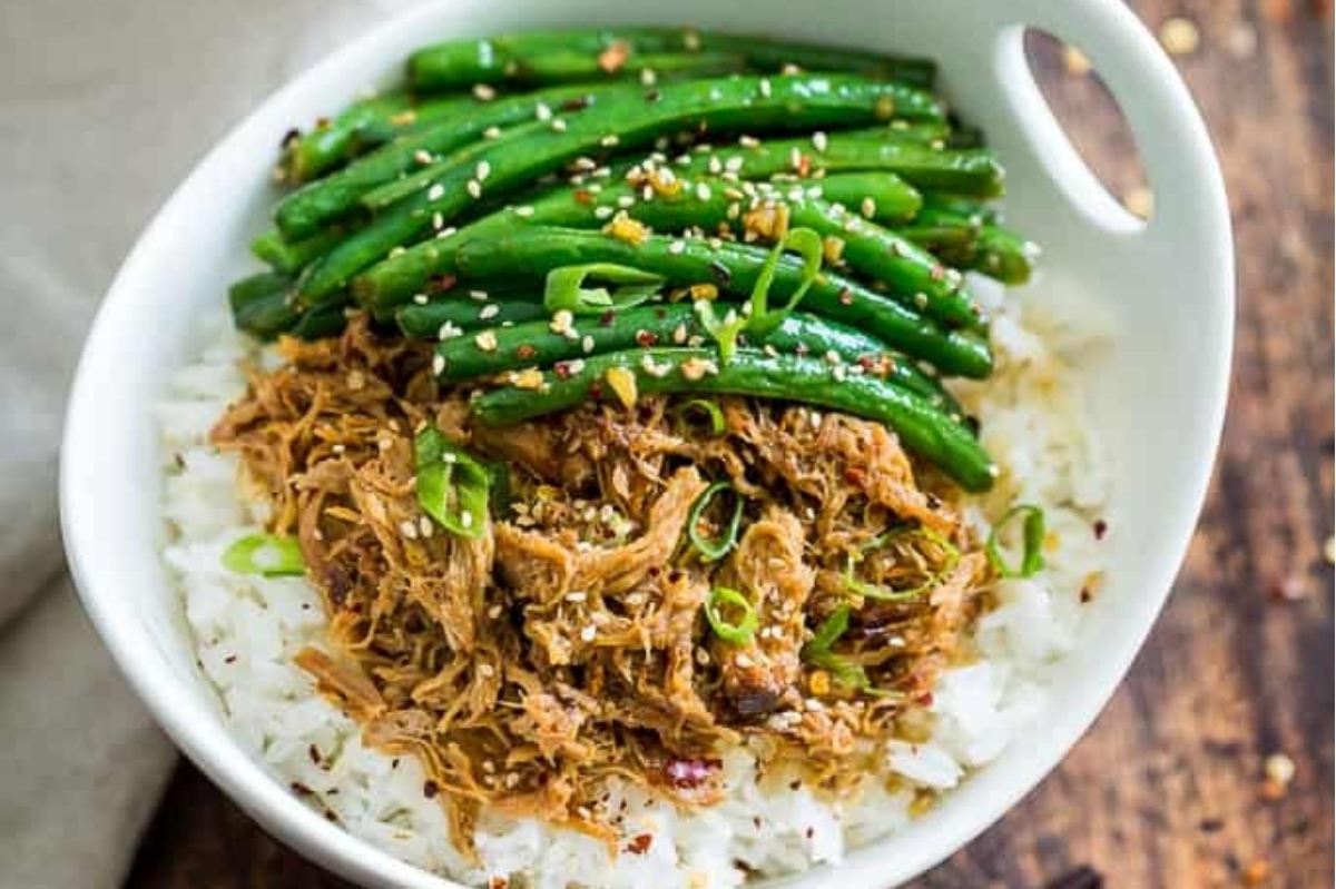A white bowl with green beans, rice and sesame seeds.