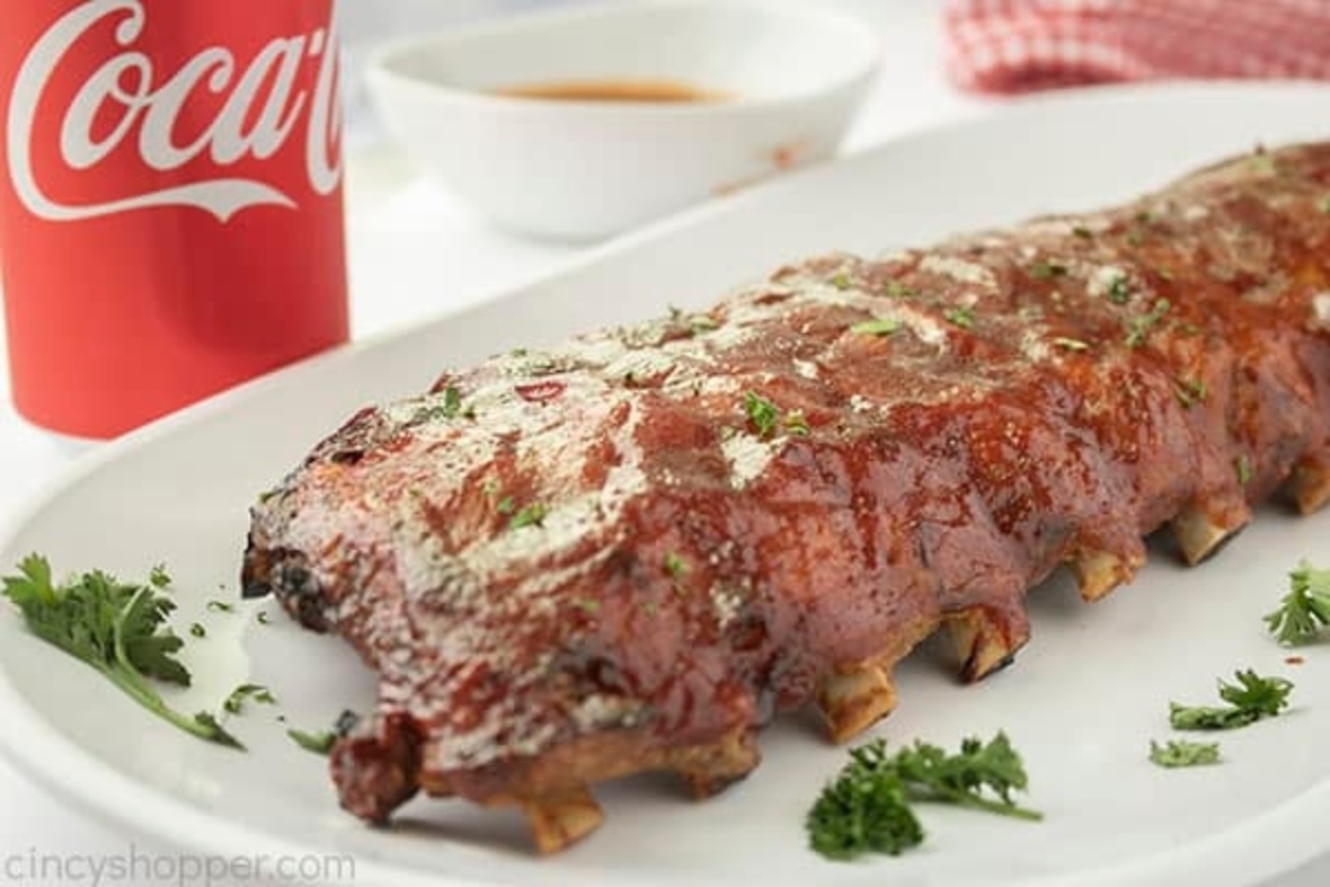 Coca cola ribs on a plate next to a coca cola.