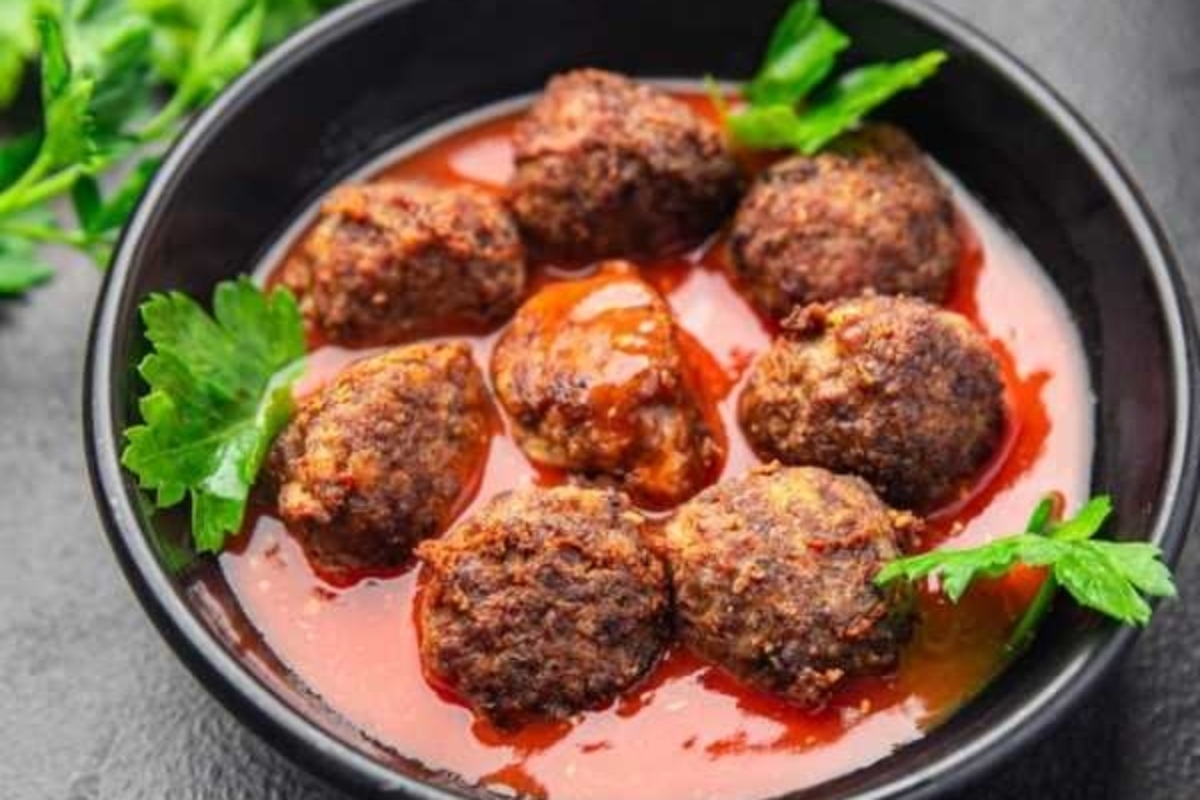 Meatballs in tomato sauce in a black bowl.