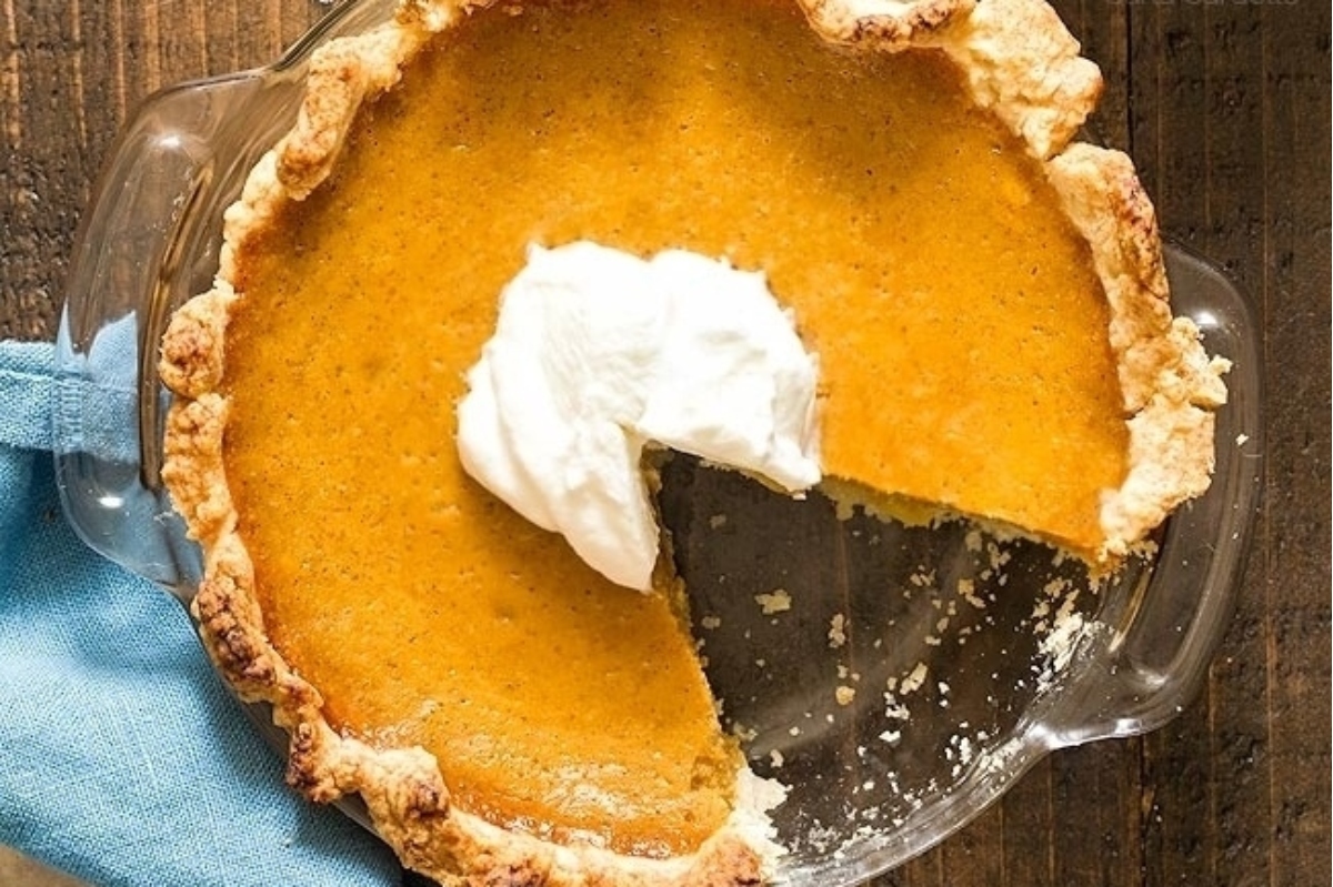 A slice of pumpkin pie with whipped cream on top.