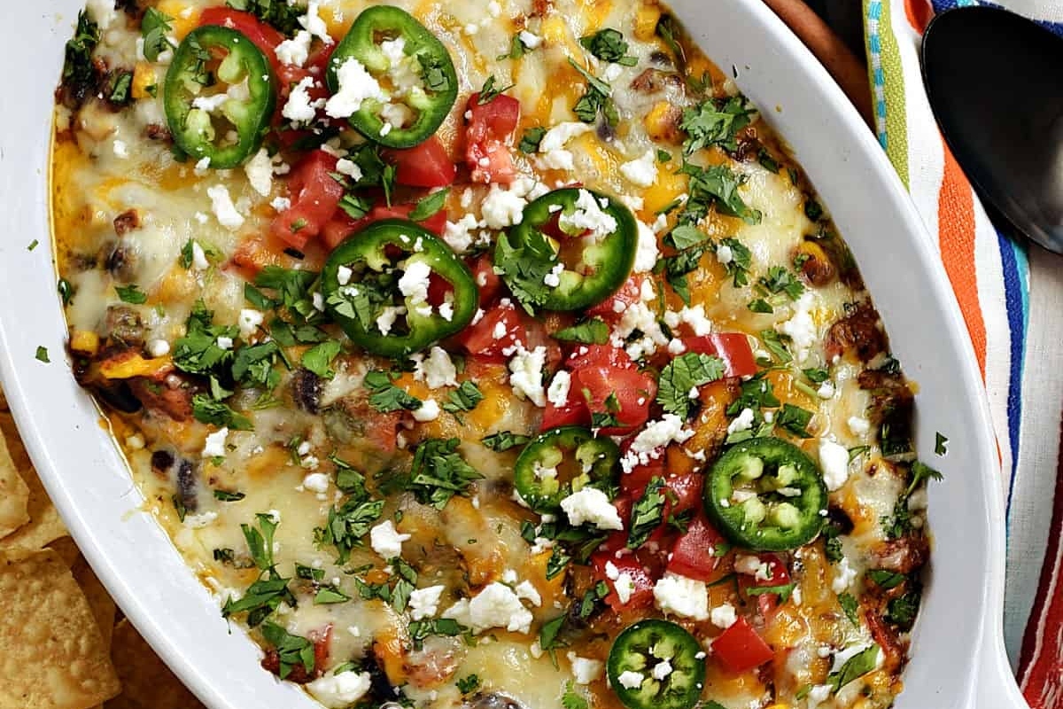 Mexican dip in a white dish with tortilla chips.