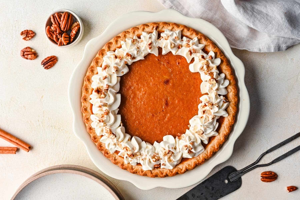 A pumpkin pie with whipped cream and pecans.