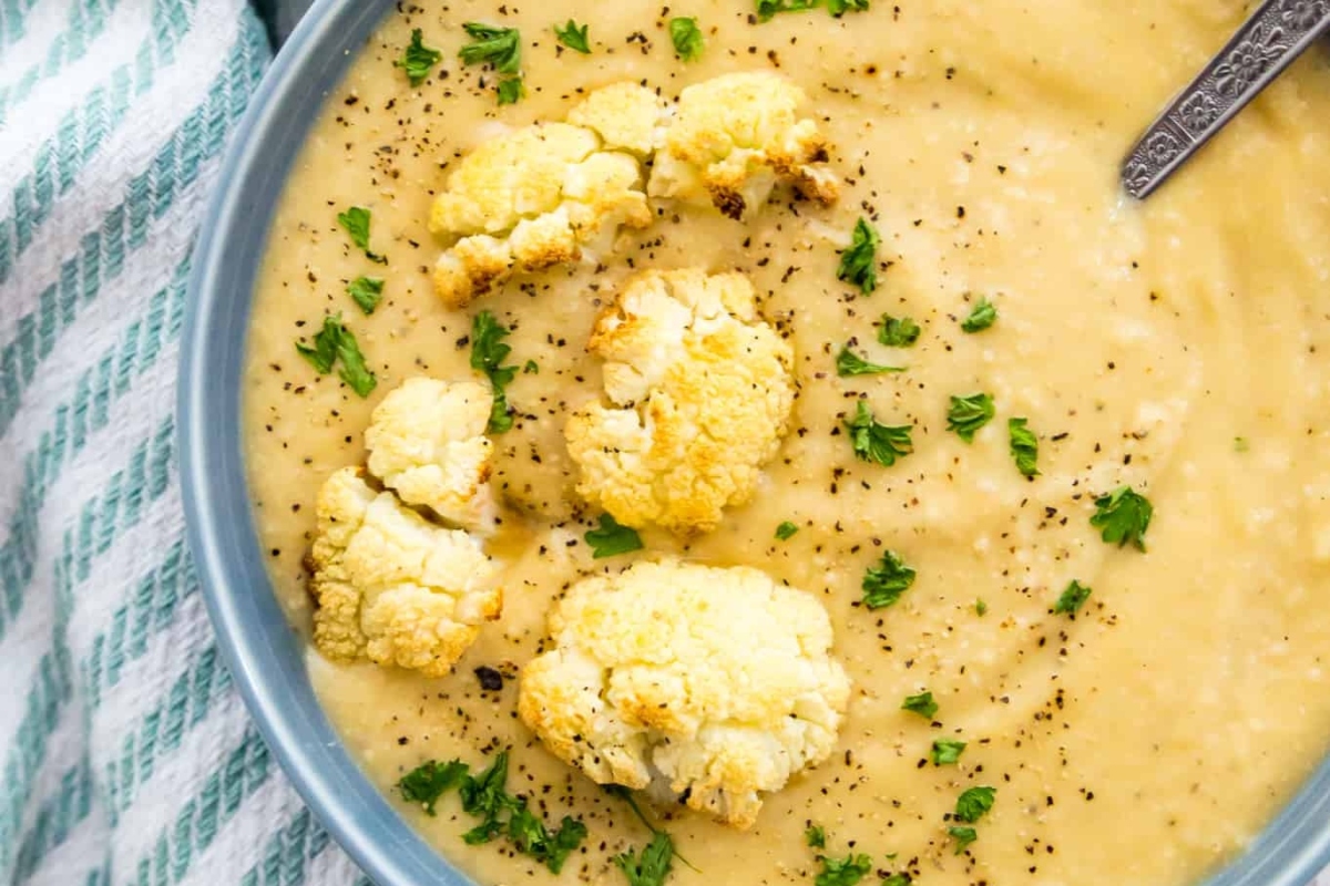 Cauliflower soup in a blue bowl with a spoon.