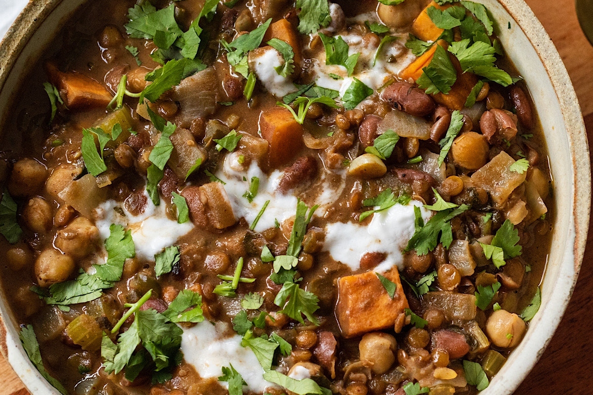 A bowl of lentils and chickpeas with sour cream.
