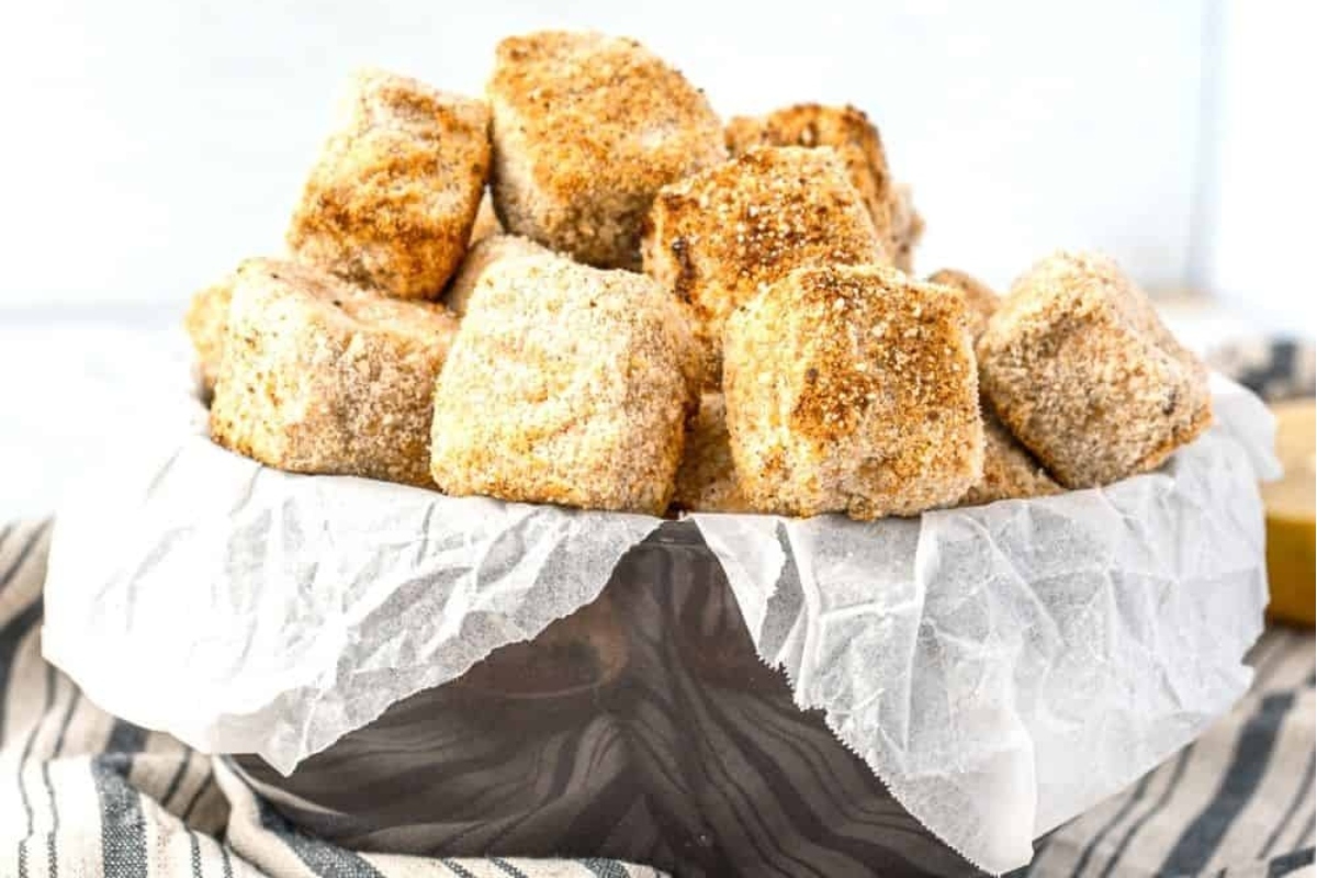 A bowl full of breaded chicken nuggets.