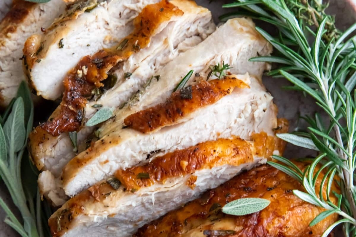 Sliced turkey with rosemary sprigs on a plate.