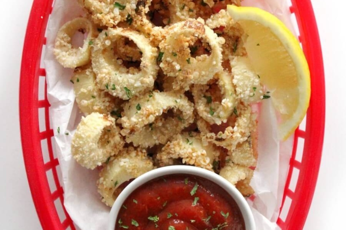 Fried octopus in a red basket with dipping sauce.