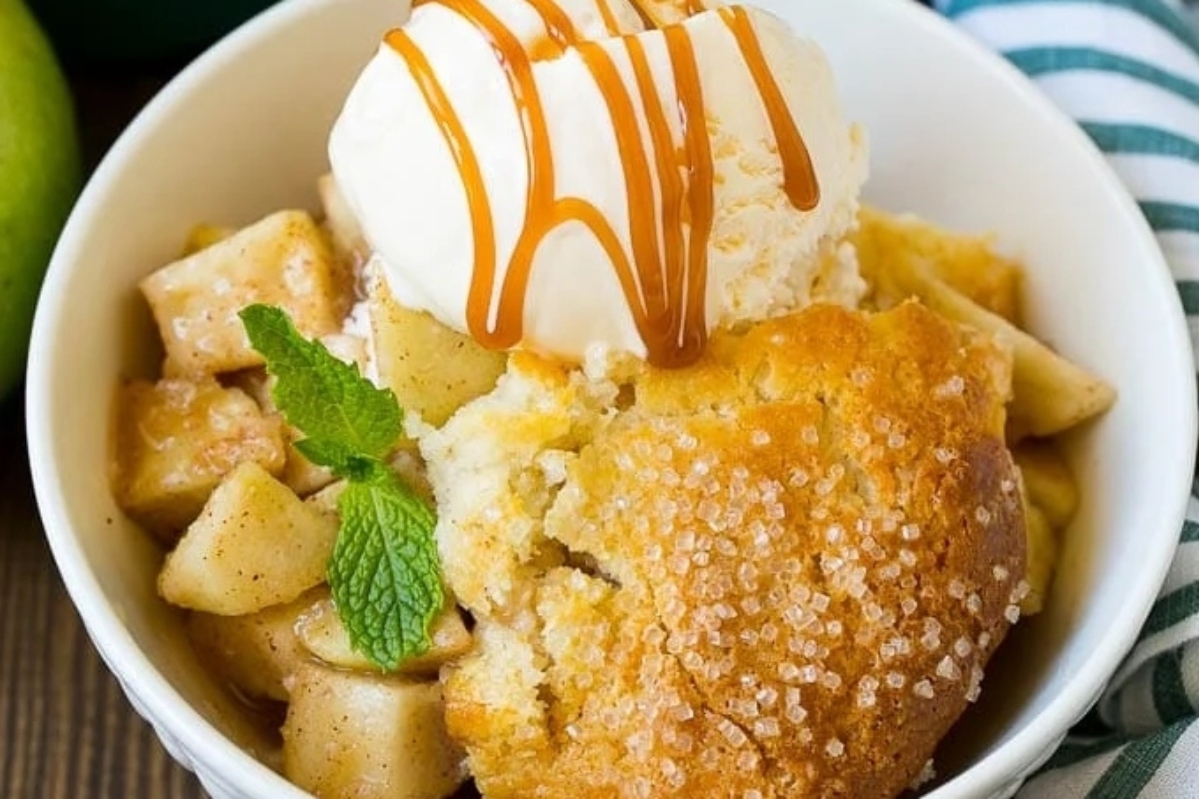 A bowl of apple cobbler with ice cream and apples.