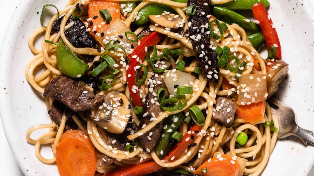 beef stir fry with noodles in white bowl.