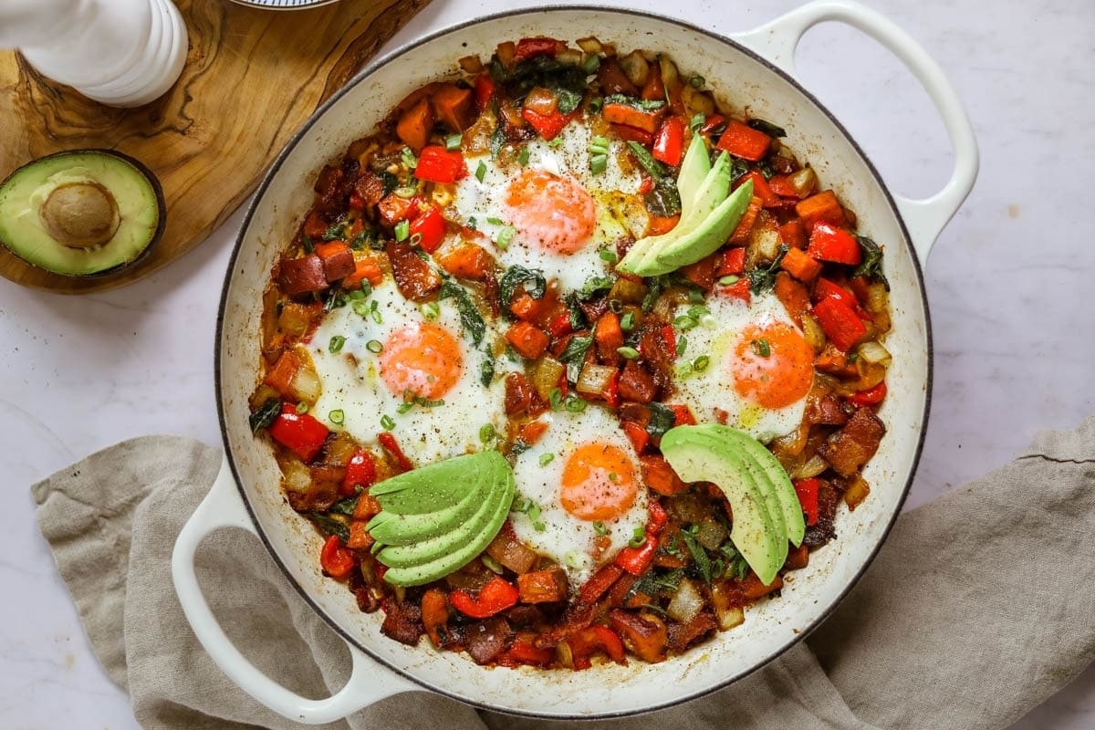 A skillet filled with eggs, avocado, and bacon.