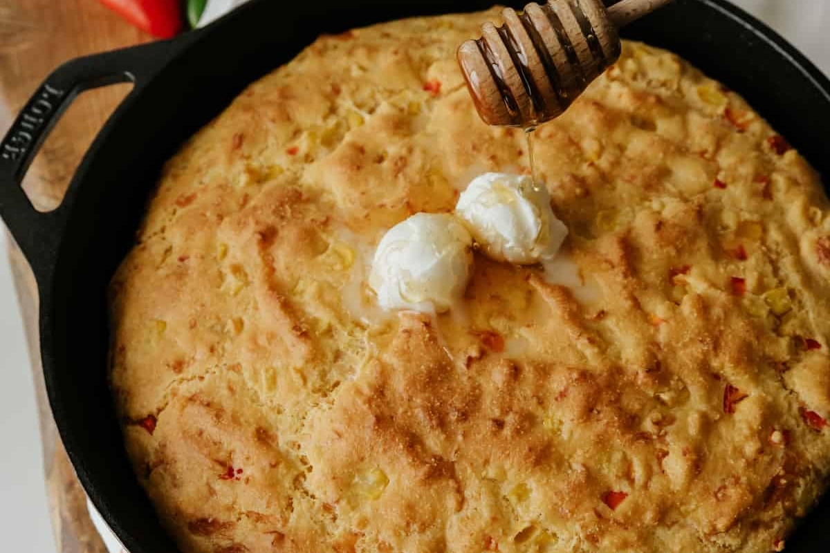Cornbread in a skillet with honey on top.