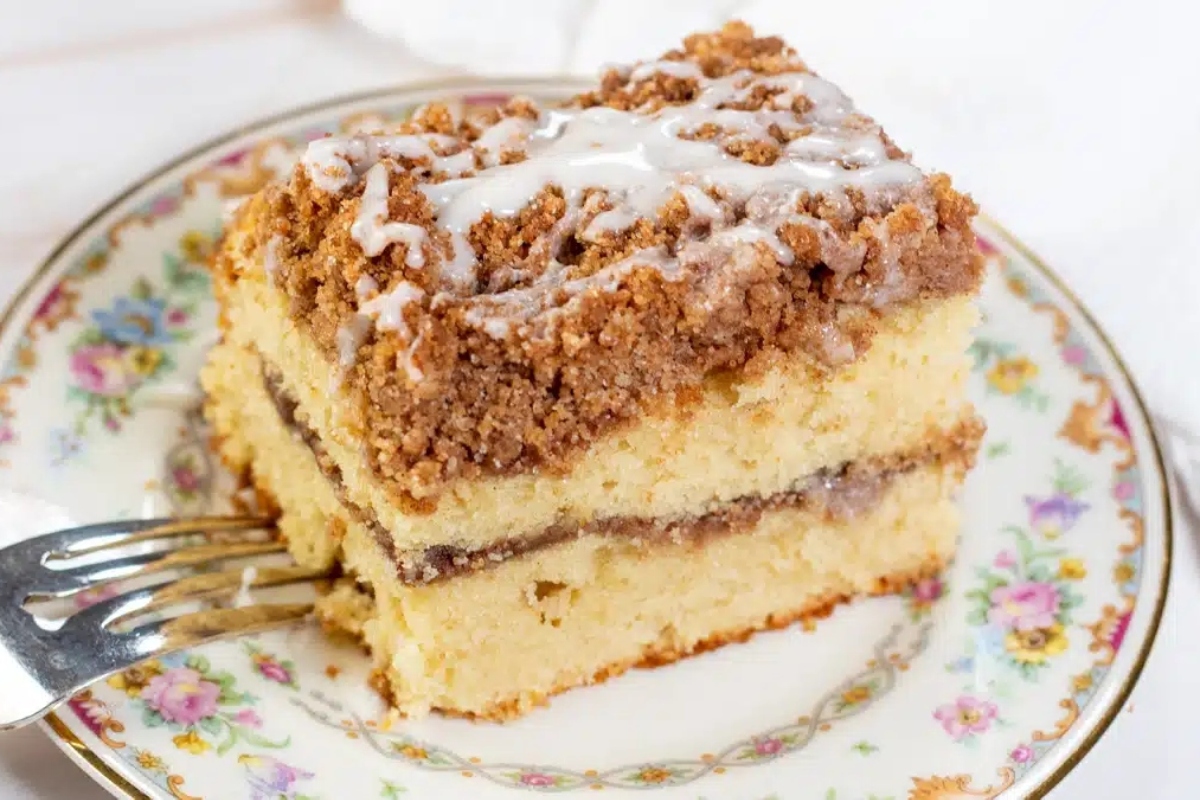 A slice of coffee cake on a plate with a fork.