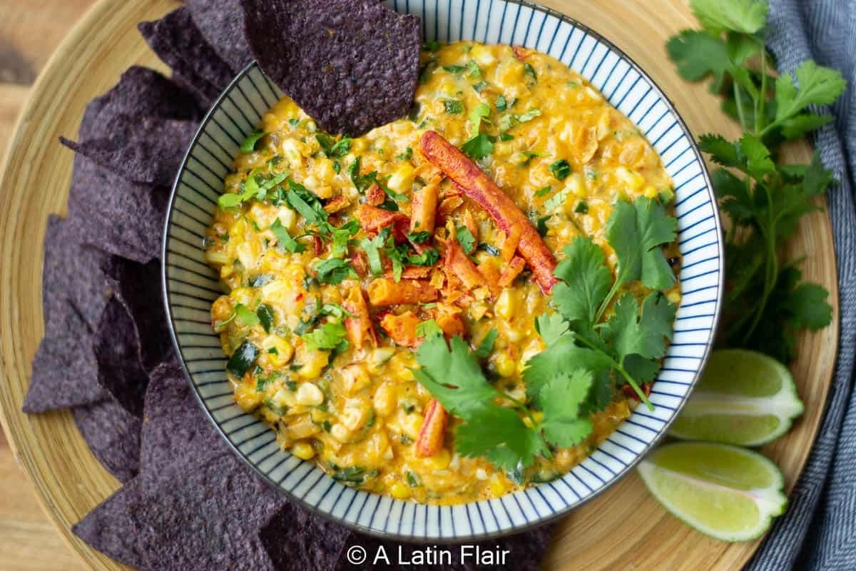 A bowl of dip with tortilla chips and garnished with cilantro.