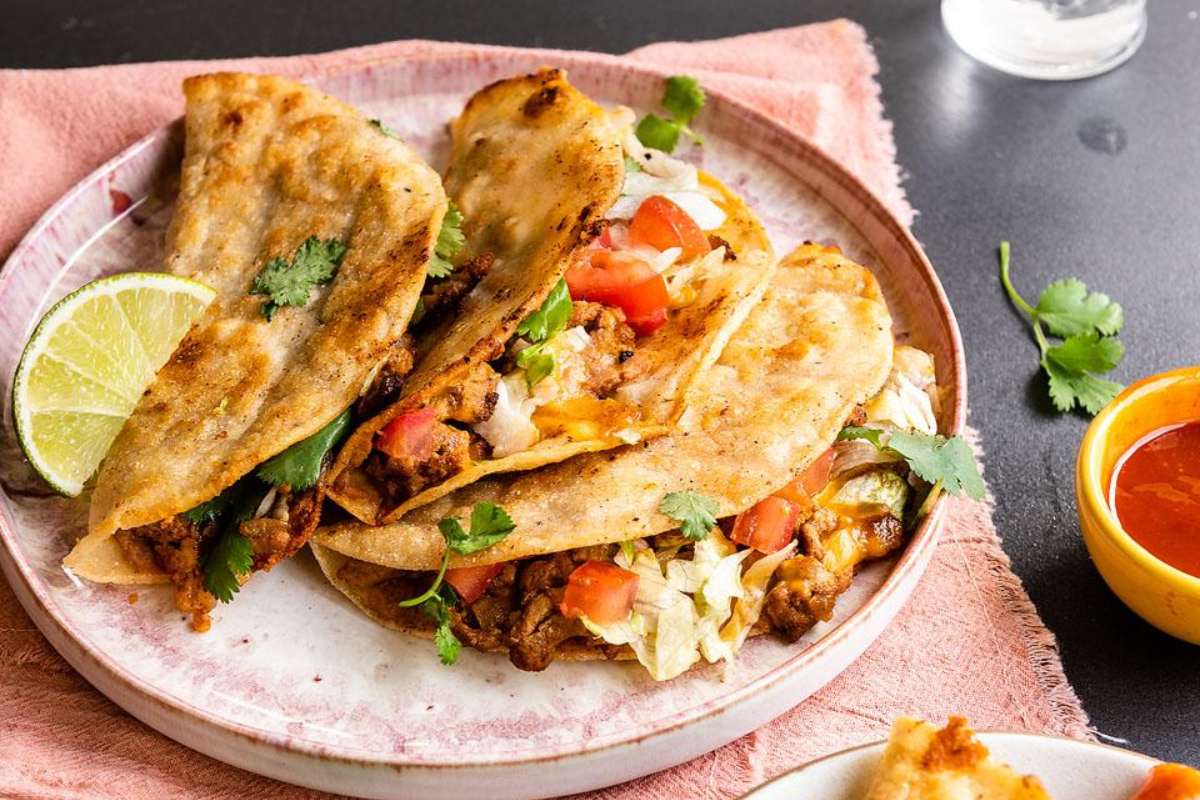 Mexican tacos on a plate with a lime wedge.