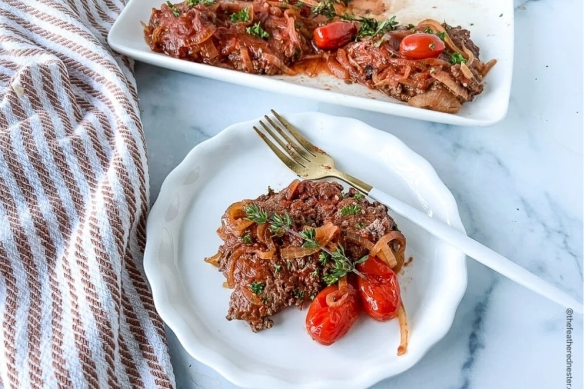 A plate with meat and tomatoes on it.