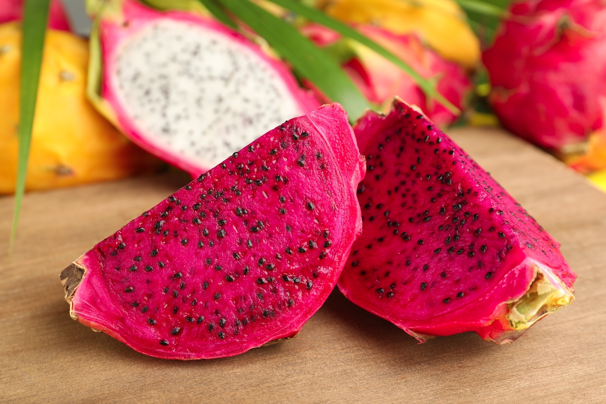 Delicious cut red pitaya dragon fruit on wooden board, closeup.