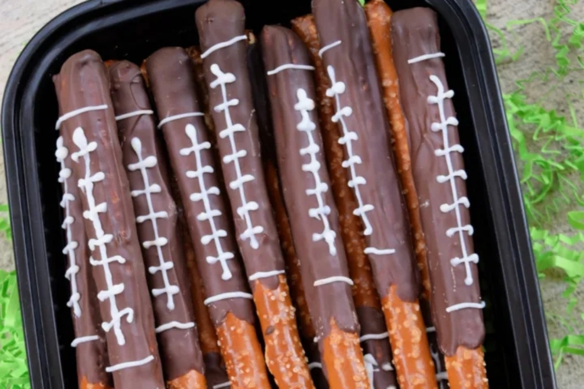 Chocolate football pretzels in a plastic container.