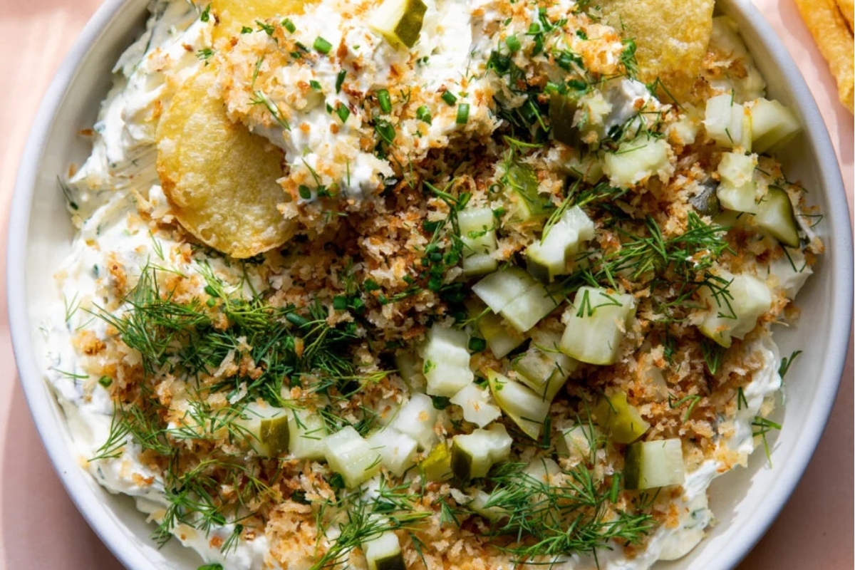 A bowl of dip with chips and dill.