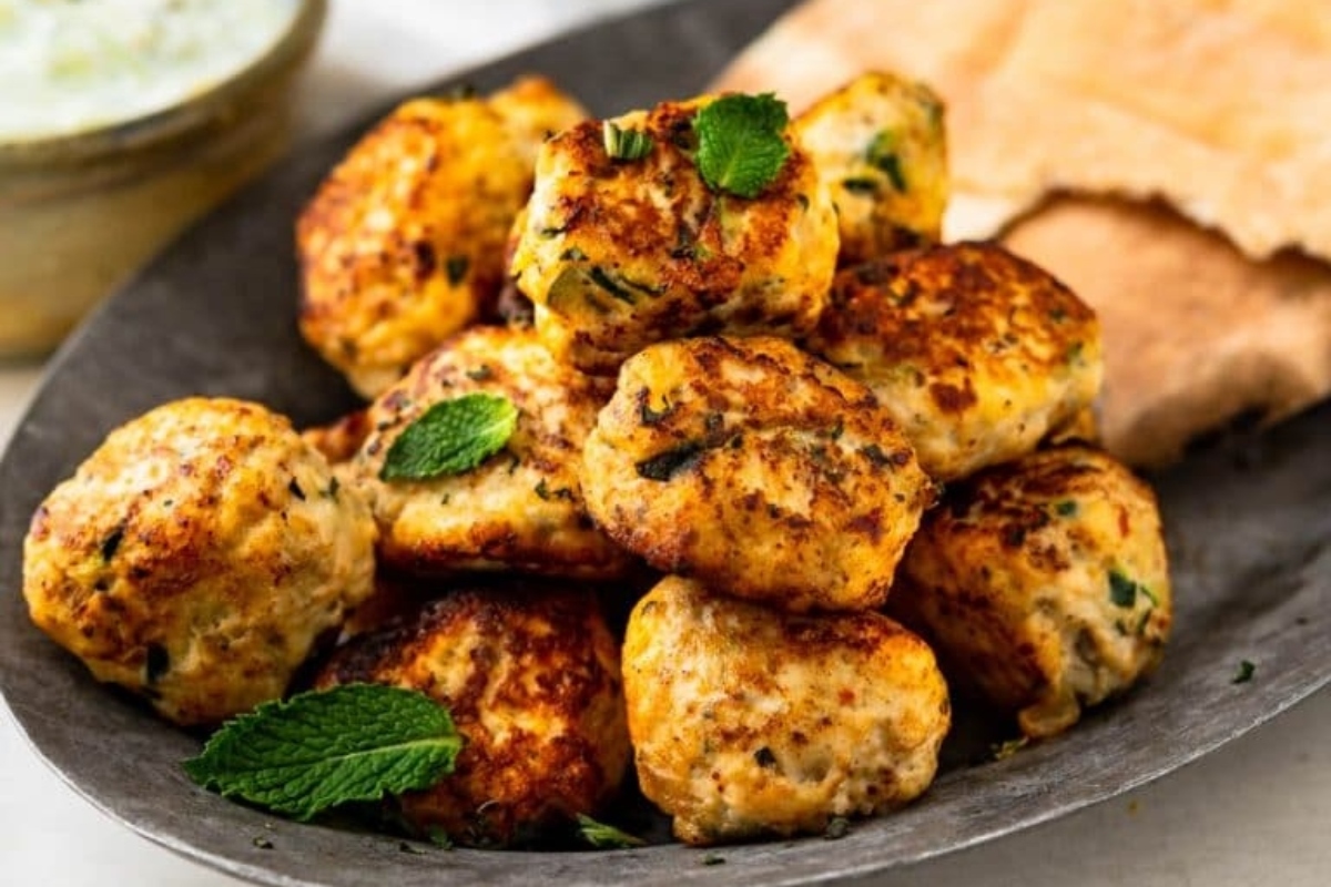 A plate of meatballs with a mint dipping sauce.