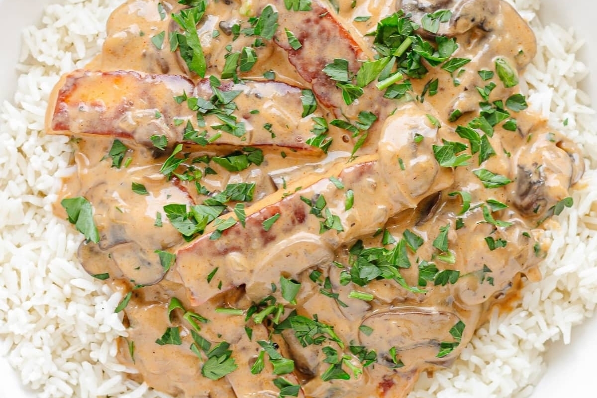 A bowl of rice with mushroom gravy and parsley.