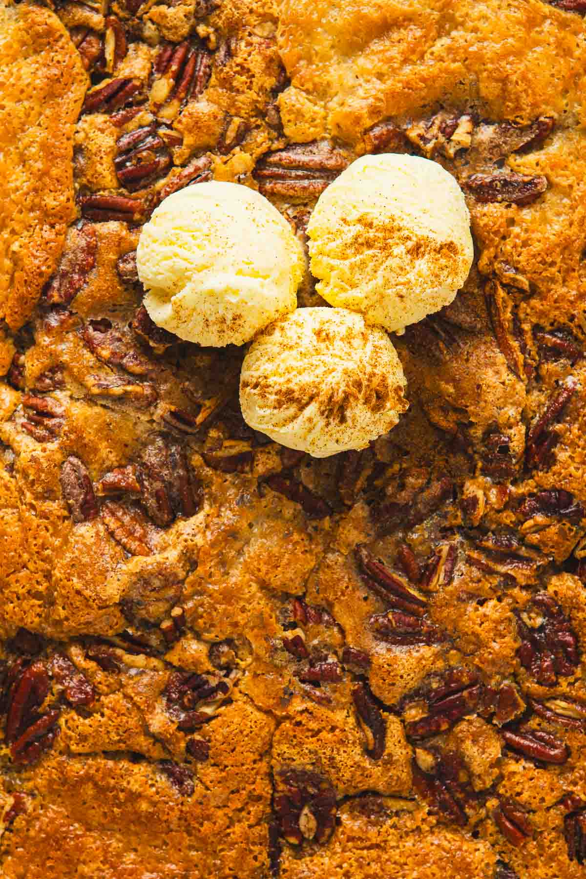 A pecan cobbler with ice cream on top.