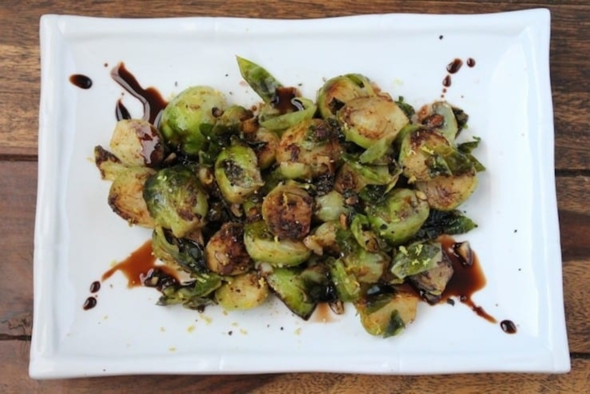 Brussels sprouts on a white plate with sauce.