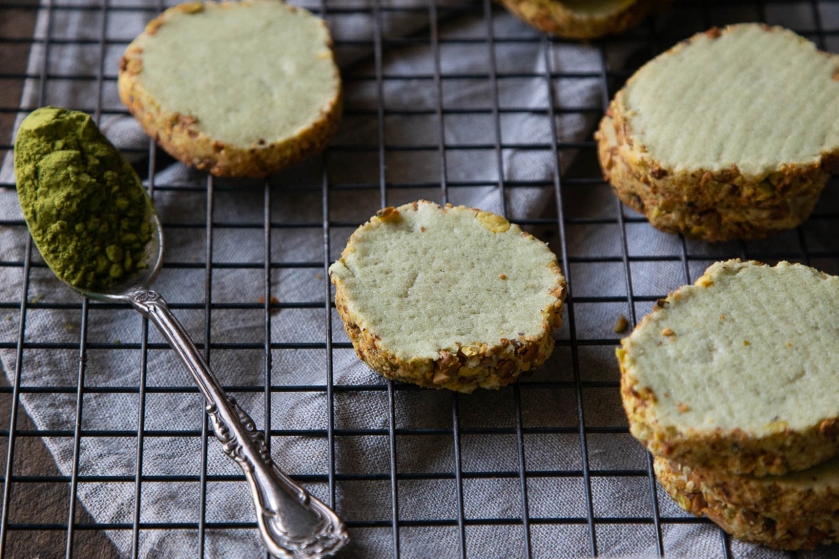 Matcha cookies on a cooling rack with a spoon.