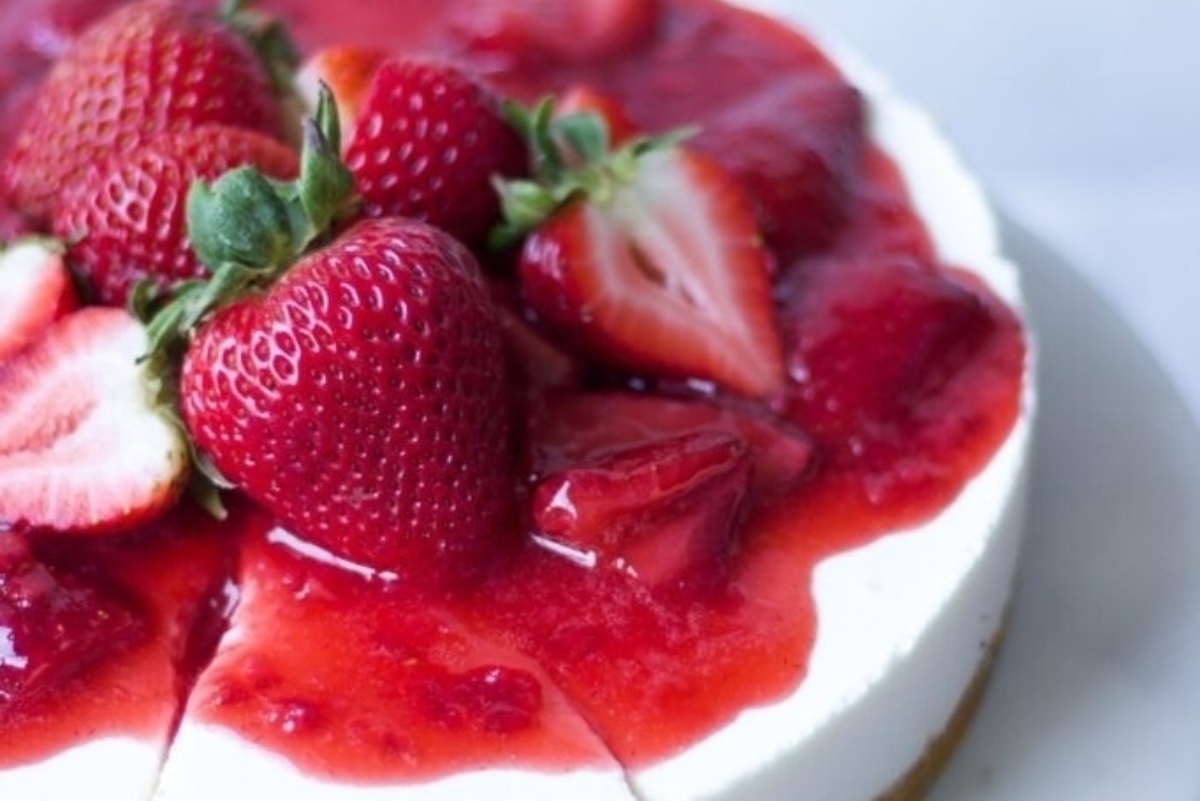 A slice of strawberry cheesecake on a white plate.