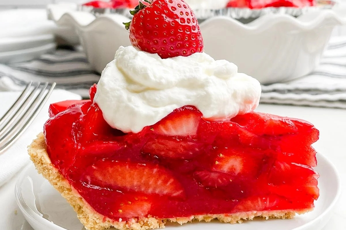 A slice of strawberry pie with whipped cream on top.