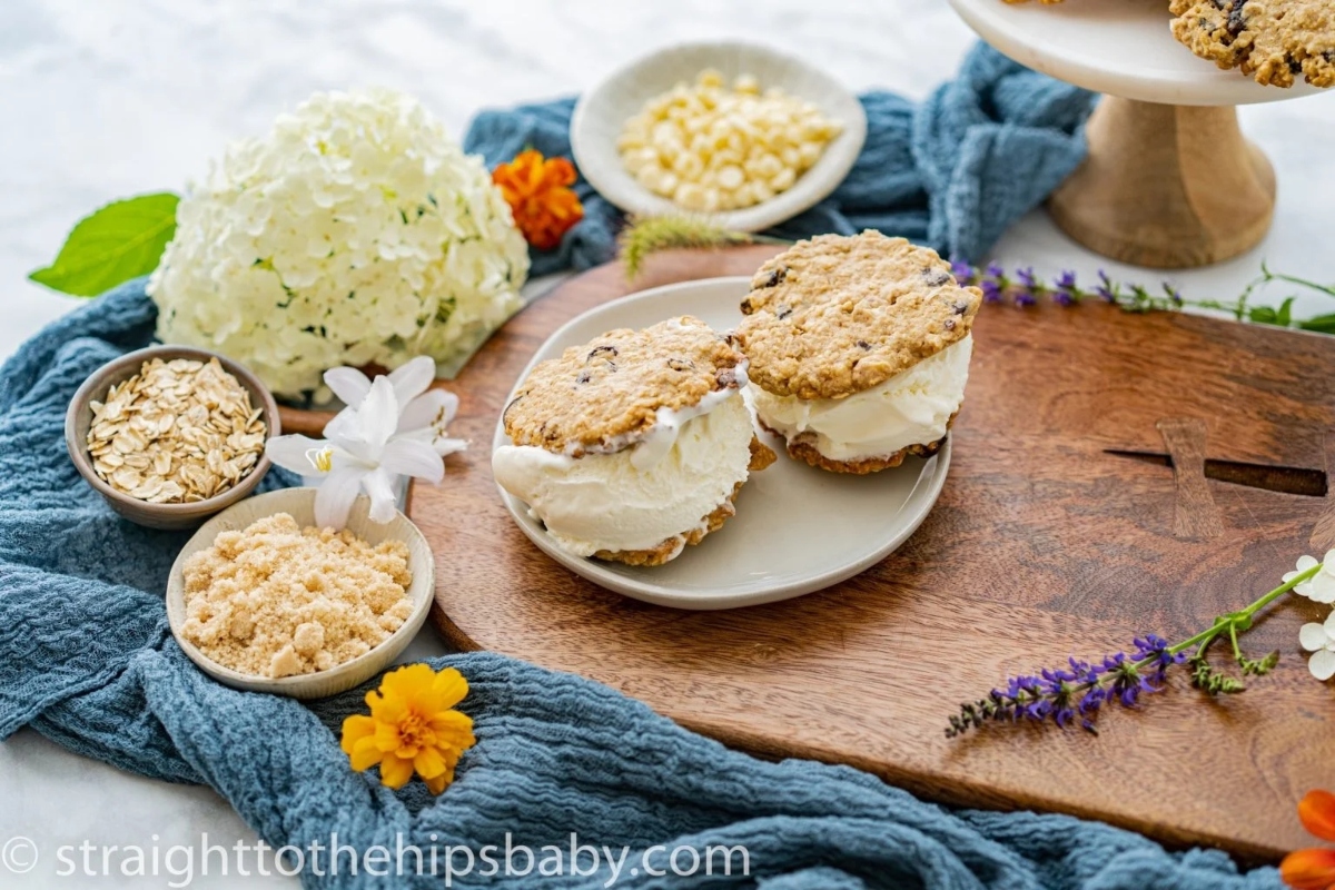 A wooden cutting board with cookies and flowers on it.