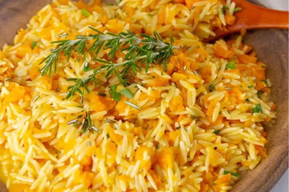 A bowl of rice with carrots and sprigs of thyme.