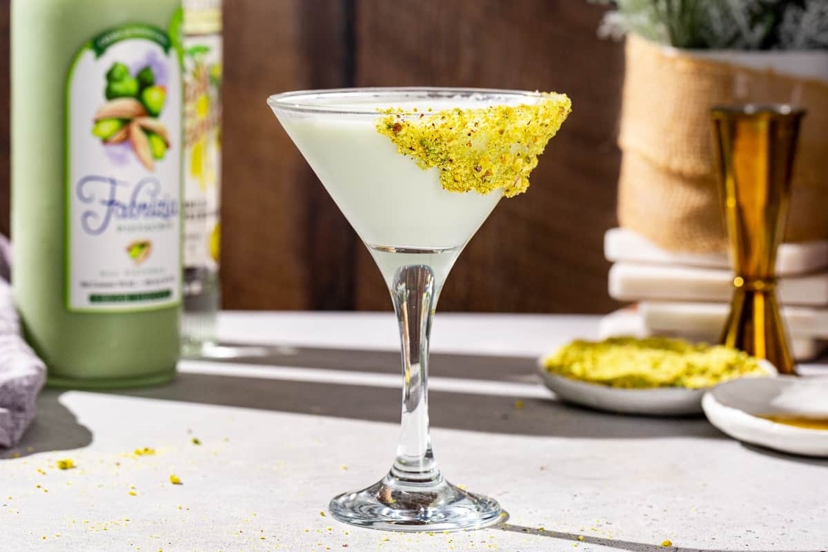 A martini with pistachios and a bottle of lemonade.