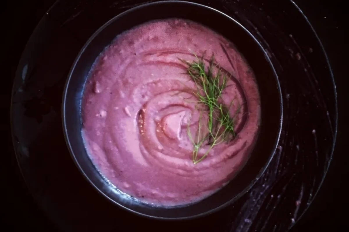 A bowl of purple soup with a sprig of dill.