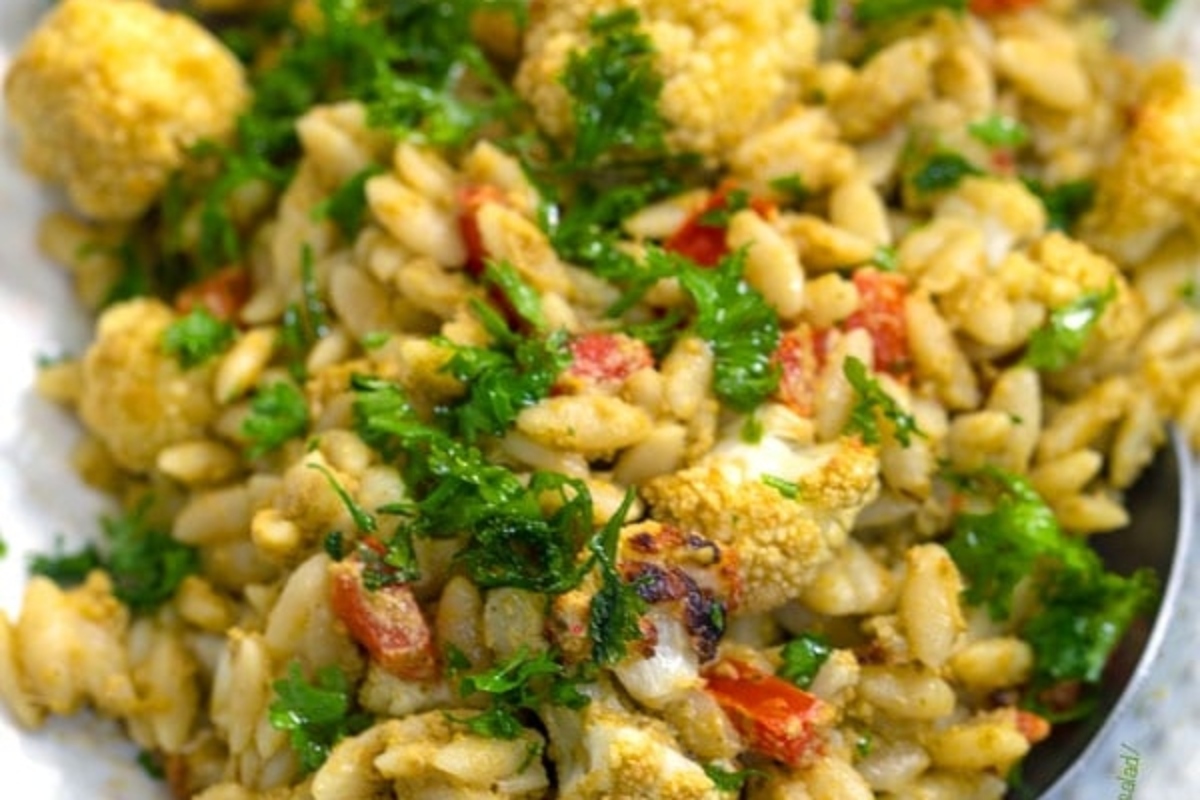 A bowl of pasta with cauliflower and parsley.