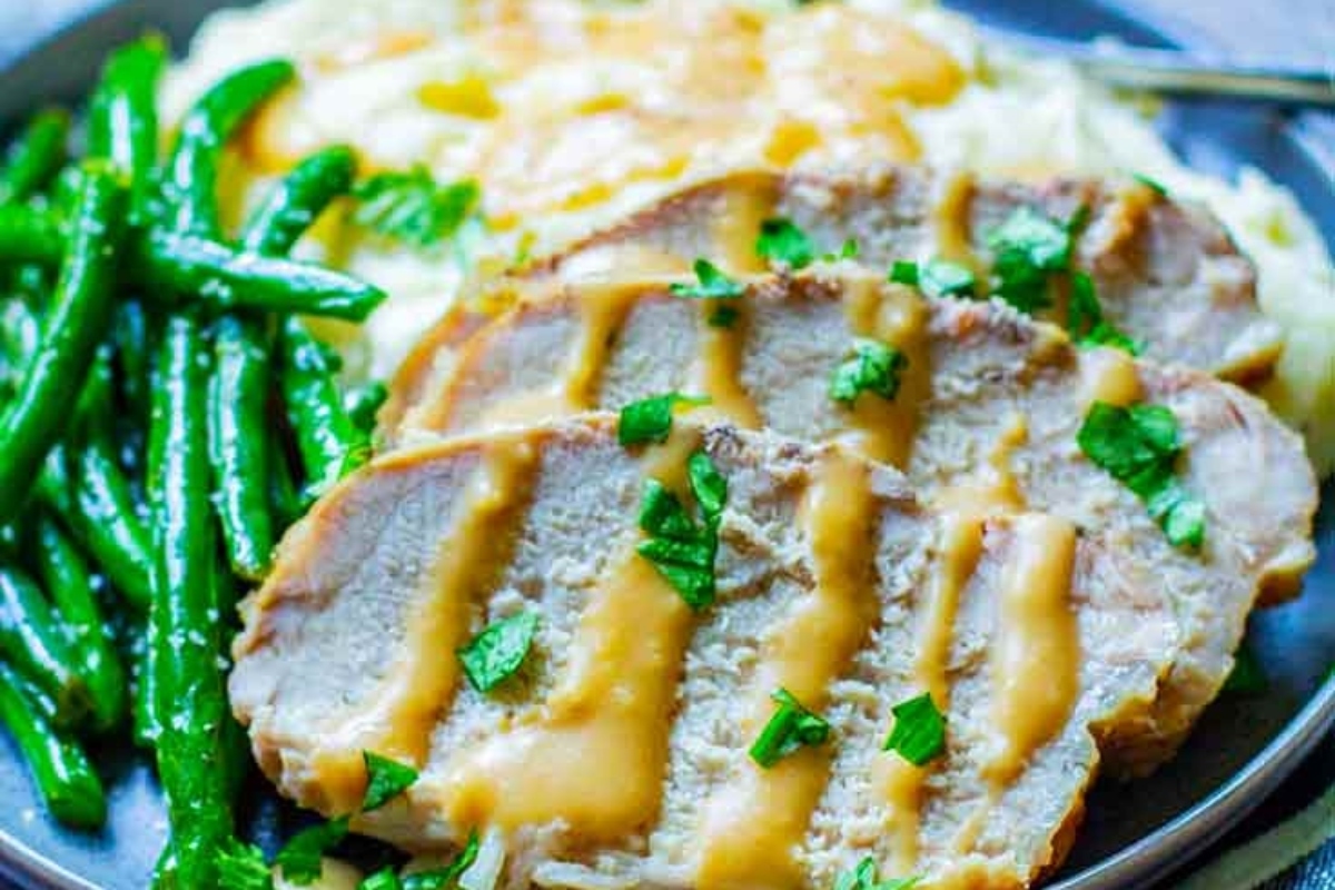 Pork chops on a plate with green beans and gravy.