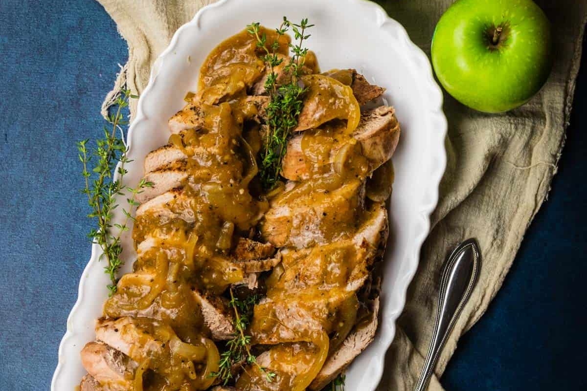 Pork tenderloin with apple sauce on a white plate.