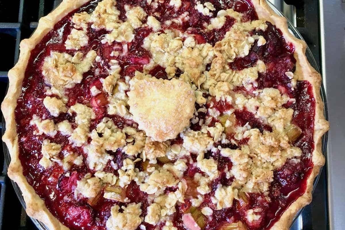 A pie with cranberry topping on top of a stove.
