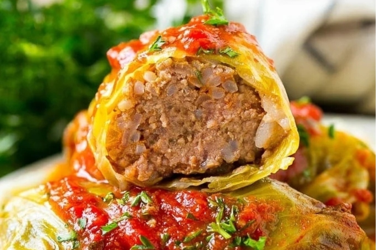 Cabbage rolls with meat and sauce on a plate.