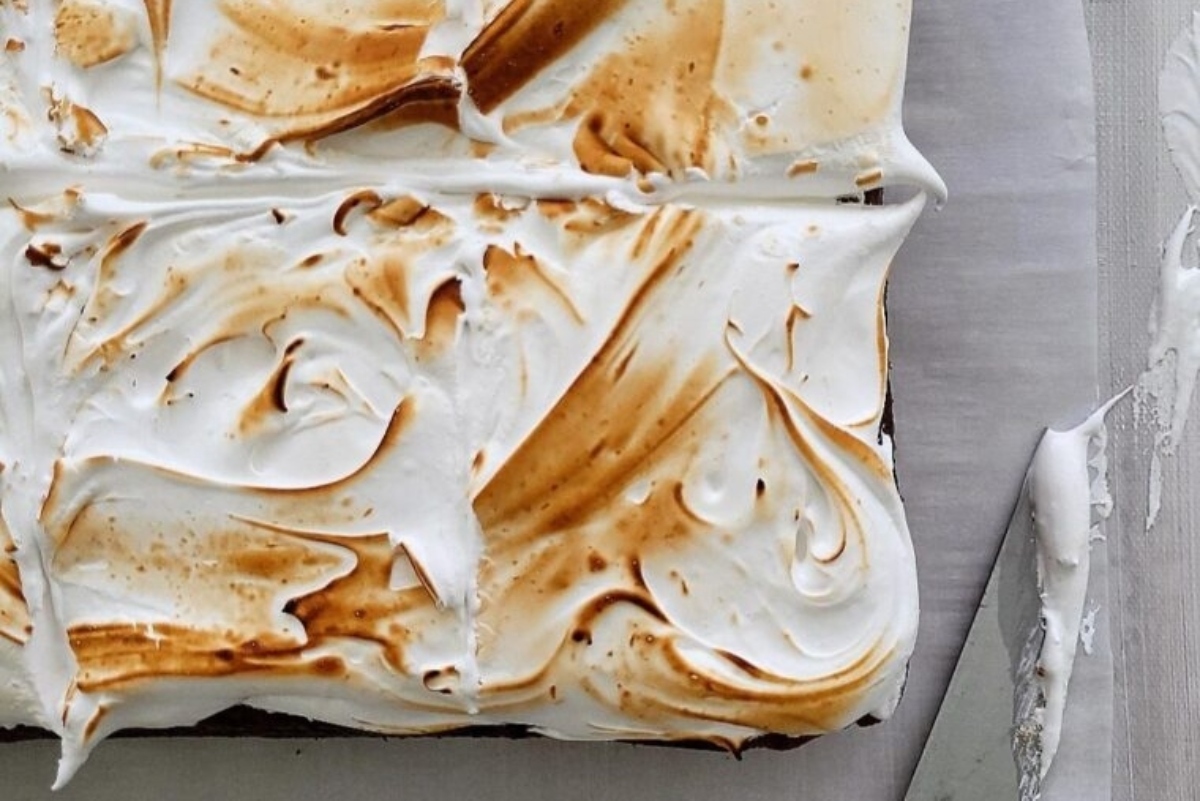 A brownie with whipped cream and a knife on top.